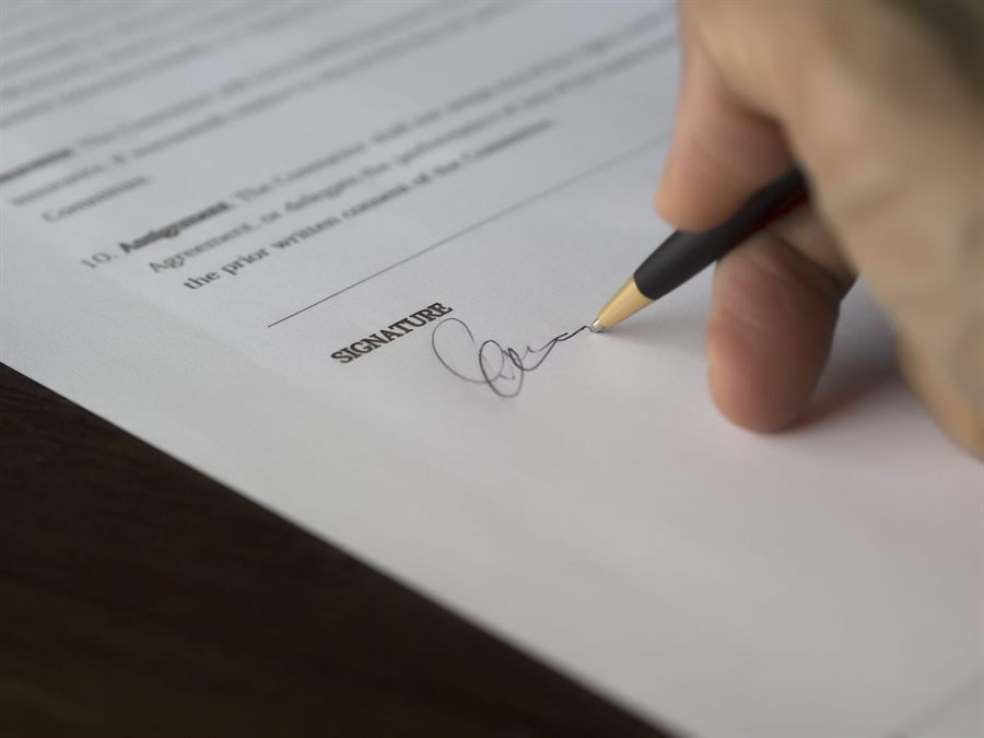Hand signing a printed contract with a pen