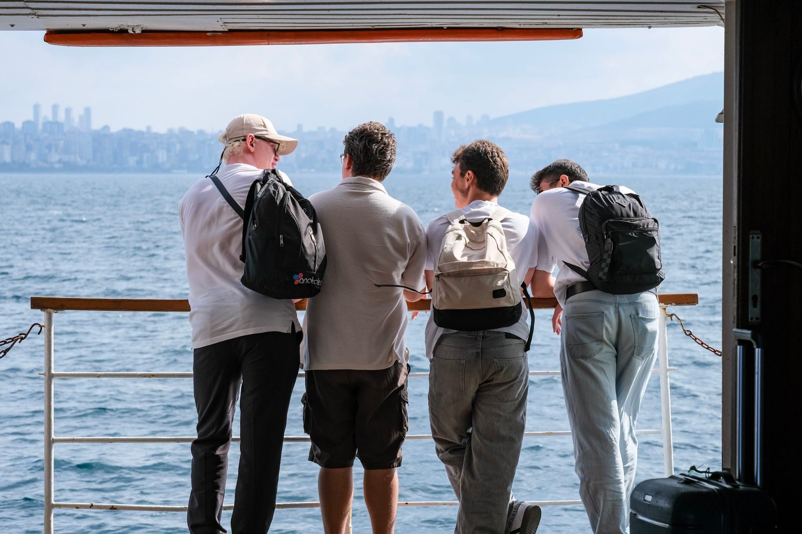 Four travelers at the rail of a boat looking out over the water; a tour conductor credit can help cover a group leader&rsquo;s cabin